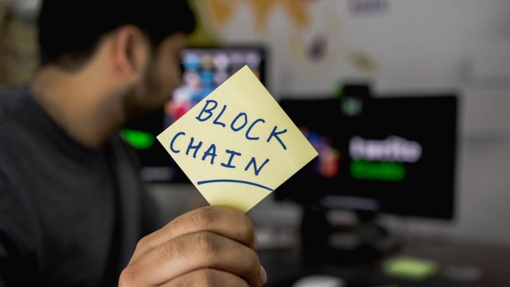 person holding sticky note that says blockchain